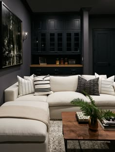 a living room with black cabinets and white couches in front of a coffee table