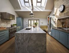 a kitchen with an island and skylight in it's center area, along with blue cabinets