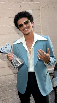 a man in a blue jacket and sunglasses holding a fan