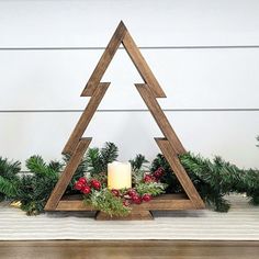 a wooden christmas tree with candles and greenery