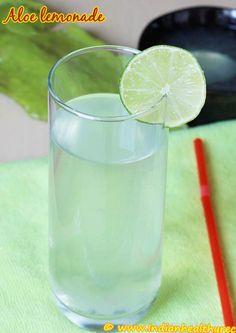 a close up of a glass with water and a lime on the rim next to a straw