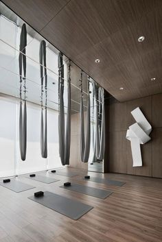 yoga mats are lined up on the floor in front of large windows with drapes