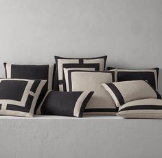 black and white pillows sitting on top of a bed next to each other in front of a gray wall