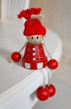 a small red doll is hanging from a white shelf with balls on it's legs