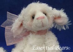 a white stuffed animal with a pink ribbon around its neck and ears, sitting on a blue background