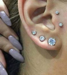 a woman's ear with three different piercings on her left side and two smaller ones