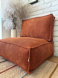 an orange couch sitting on top of a rug next to a white brick wall