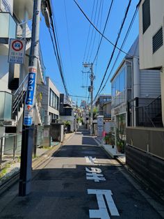 an empty street with power lines above it and buildings on both sides, in the background