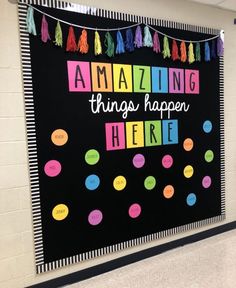 a bulletin board with the words amazing things happen here written in bright colors on it