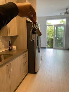 a person is pouring coffee into a mug in a kitchen with white cabinets and wood floors