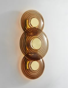 three brown glass plates sitting on top of a white wall next to each other in the shape of circles