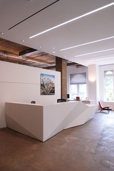 an empty reception area with white walls and wood beams on the ceiling, along with modern furniture