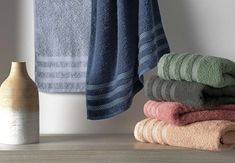 towels are stacked on top of each other next to a vase