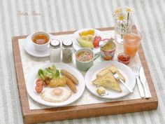 a tray filled with breakfast foods on top of a white and brown striped table cloth