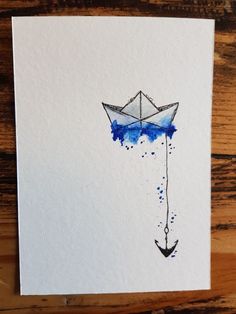 an origami boat floating in the water on top of a white card with blue ink