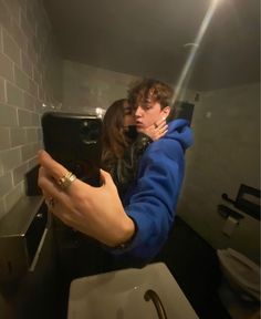 a man and woman taking a selfie in a bathroom mirror with their arms around each other