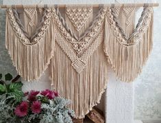 a vase with flowers sitting next to a fireplace covered in macrame fringes