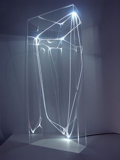 an illuminated object in the middle of a room with white walls and flooring on it