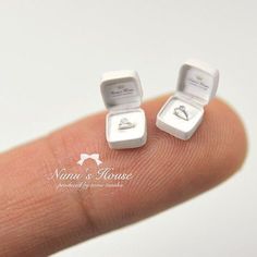 two small white boxes sitting on top of a finger