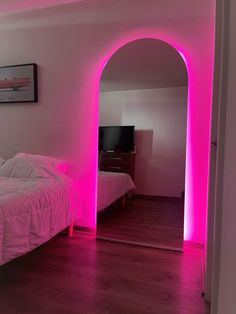 a bed sitting in a bedroom next to a pink light on the wall above it