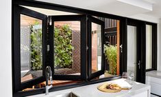 a kitchen with an open window that has plants on the windowsill and in front of it is a stainless steel sink