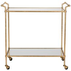 a gold metal and glass bar cart with two shelves on casteors, one shelf is empty