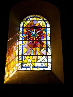 a stained glass window in the middle of a building with light coming from it's windows