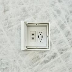 an electrical outlet in the middle of a white marble wall with two black and one white outlets