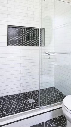 a white toilet sitting next to a shower in a bathroom with black and white tile