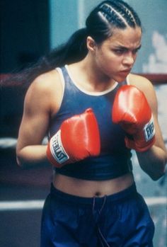 a woman wearing red boxing gloves standing next to a punching bag