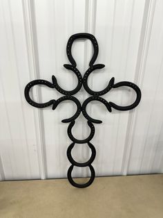 a cross made out of horseshoes on top of a wooden table next to a white wall