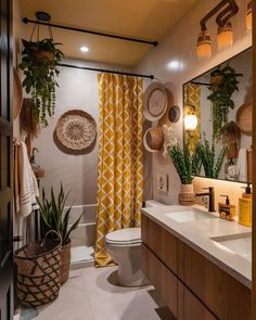 a bathroom with a toilet, sink and shower curtain in the window is decorated with potted plants