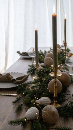 a long table with candles, plates and napkins on it is decorated for christmas