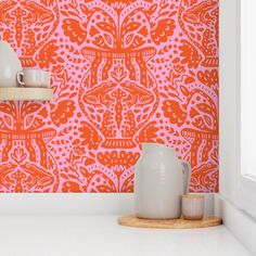 an orange and pink wallpaper with white vases next to it on a shelf