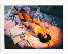 a woman laying on top of a bed next to an open book