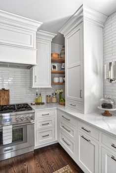 a kitchen with white cabinets and wood floors