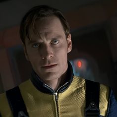 a man in a yellow and blue jacket looking at the camera with an evil look on his face