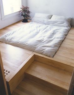 a bed sitting on top of a wooden floor next to a window