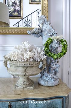 a vase with flowers sitting on top of a table next to a mirror and lamp