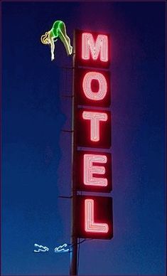 a neon sign that is on the side of a building in front of a blue sky