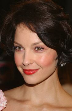 a woman in a strapless dress smiling at the camera with red lipstick on her lips