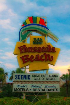 the neon sign for an ocean resort in front of palm trees and blue sky with clouds