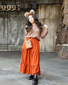 a woman in an orange skirt is posing for the camera with her hand on her hip