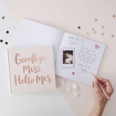 someone holding a pen and writing on a greeting card next to an envelope with a photo