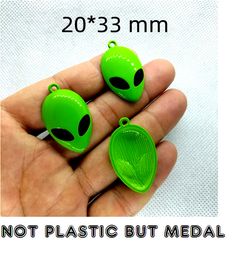 two green alien shaped plastic buttons in the palm of someone's hand, with text stating not plastic but medical