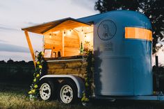 a small trailer with flowers on the side and lights in the back is lit up at night