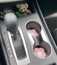 an automatic gear box with two cup holders and a teddy bear in the center console