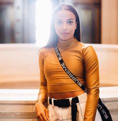 a woman standing in front of a fountain with her hands on her hips and looking at the camera