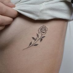 a woman's stomach with a small flower tattoo on her left side ribcage