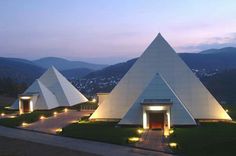 three pyramid shaped buildings lit up at night in front of the mountains and city skyline